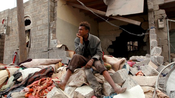 A Yemeni man sits amid the rubble of his family house that is damaged by an air-strike