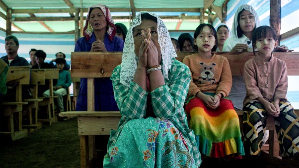 Children and their parents praying in a temporary church at a camp for internally displaced people in Myanmar.