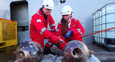 Two archaeologists examine ancient jars from shipwreck