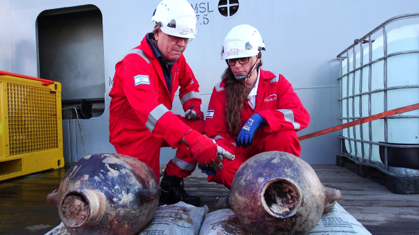 Two archaeologists examine ancient jars from shipwreck