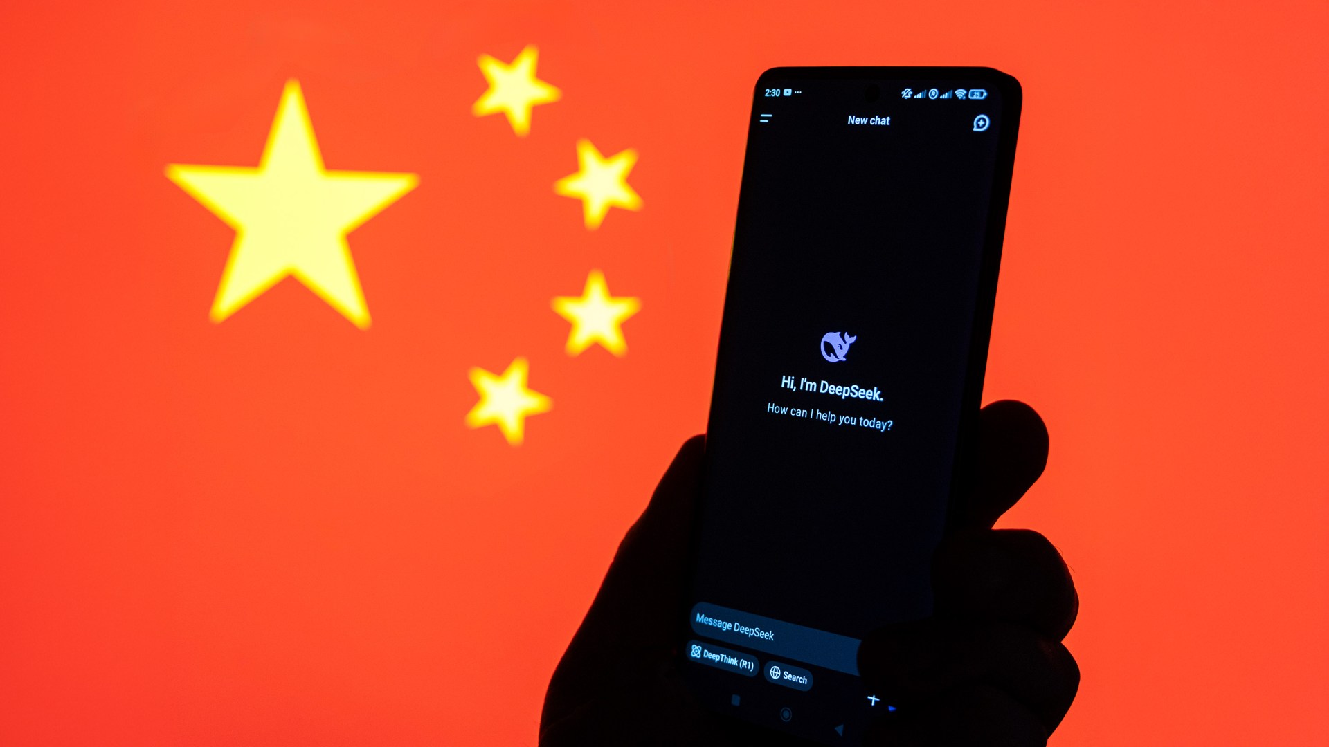 A hand holding a phone showing the DeepSeek app with the Chinese flag in the background.