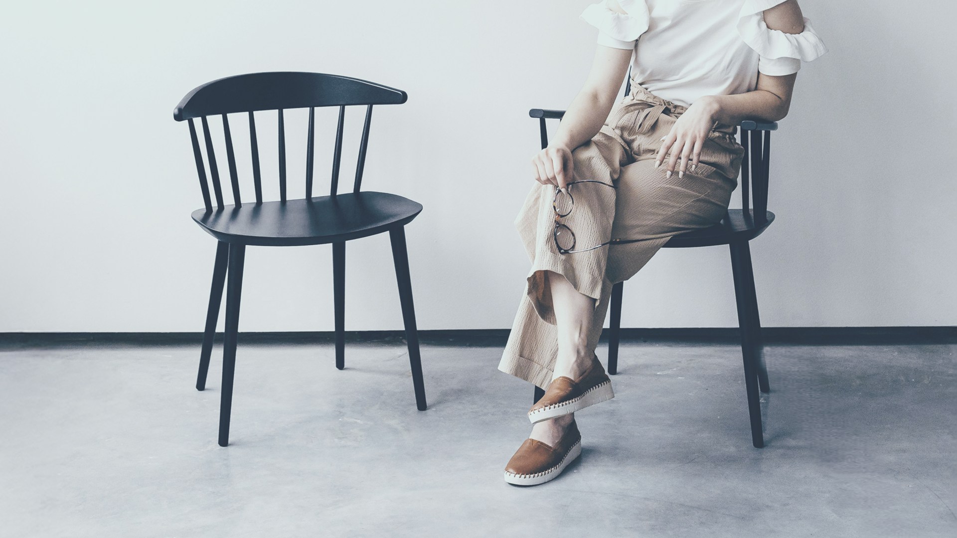 A woman thoughtfully sitting alone beside an empty chair.